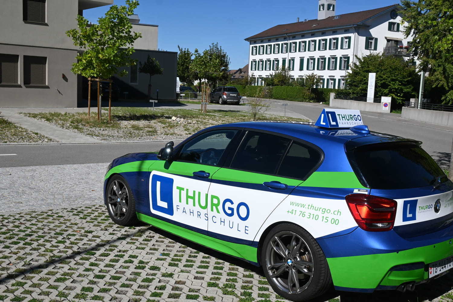 Fahrschulauto der Thurgo Fahrschule in Münchwilen TG vor einem öffentlichen Gebäude bei sonnigem Wetter