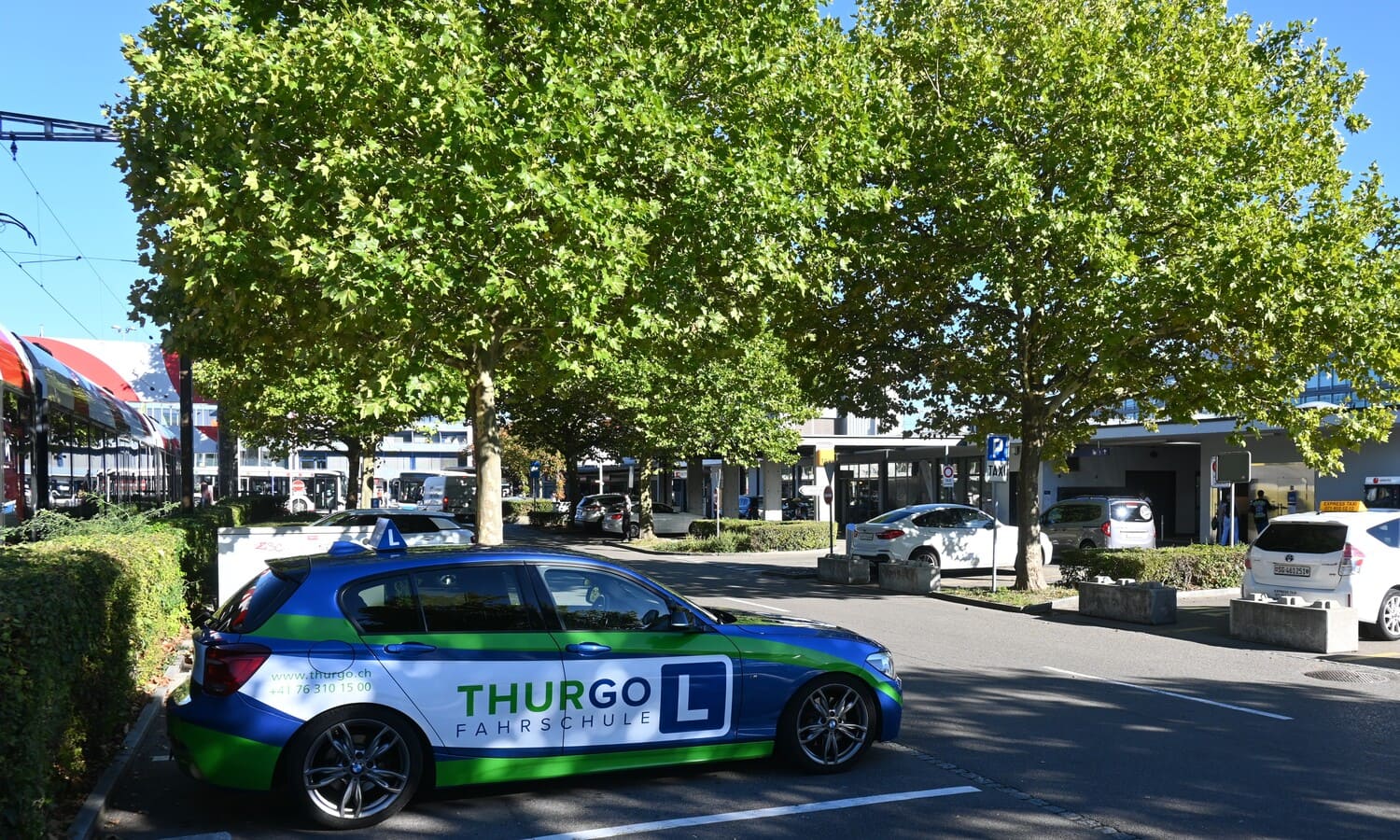 Fahrschulauto der Thurgo Fahrschule beim Wil Bahnhof auf einem Parkplatz nahe Taxistand und öffentlichem Verkehr
